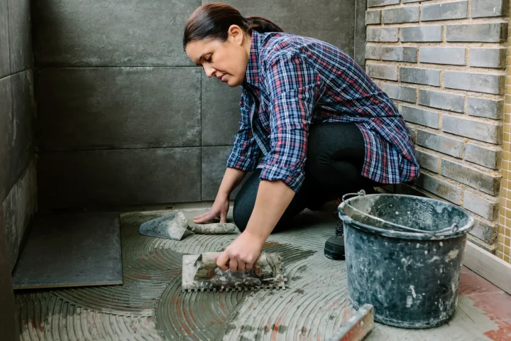 A female mason laying tiles on a terrace.