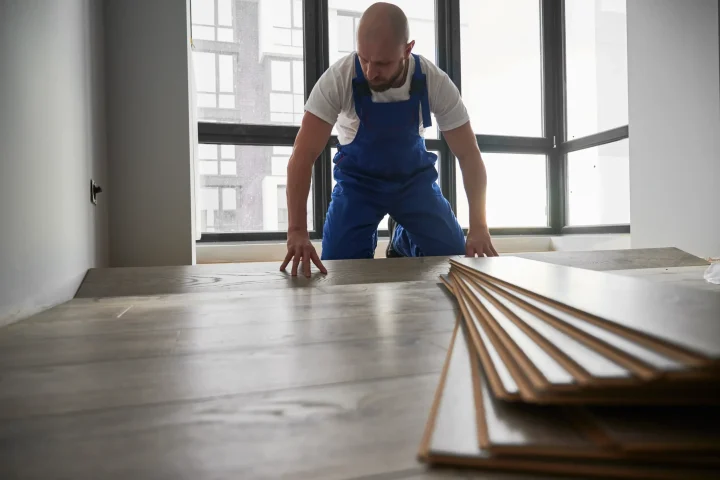 A man installing laminate flooring at home during redesign.