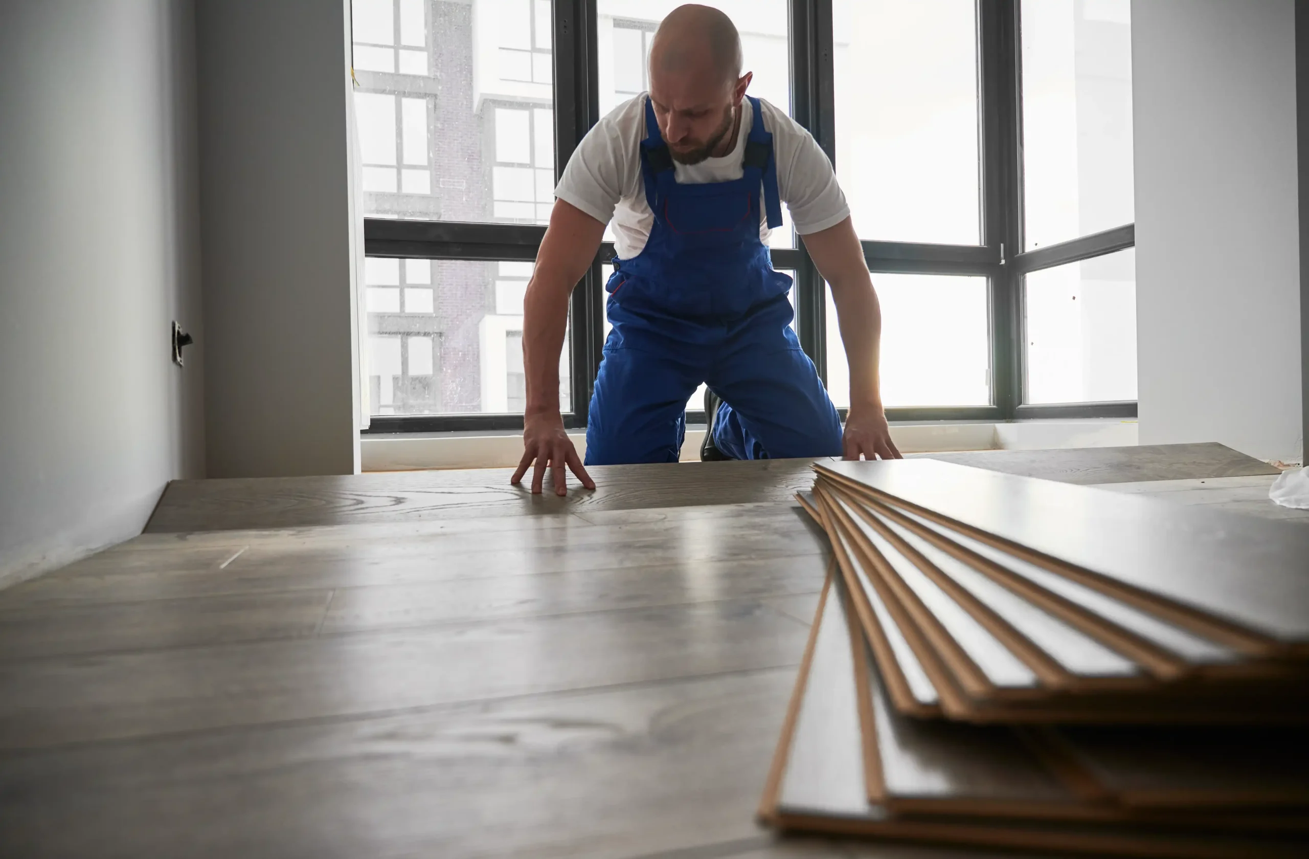 A man installing laminate flooring at home during redesign.