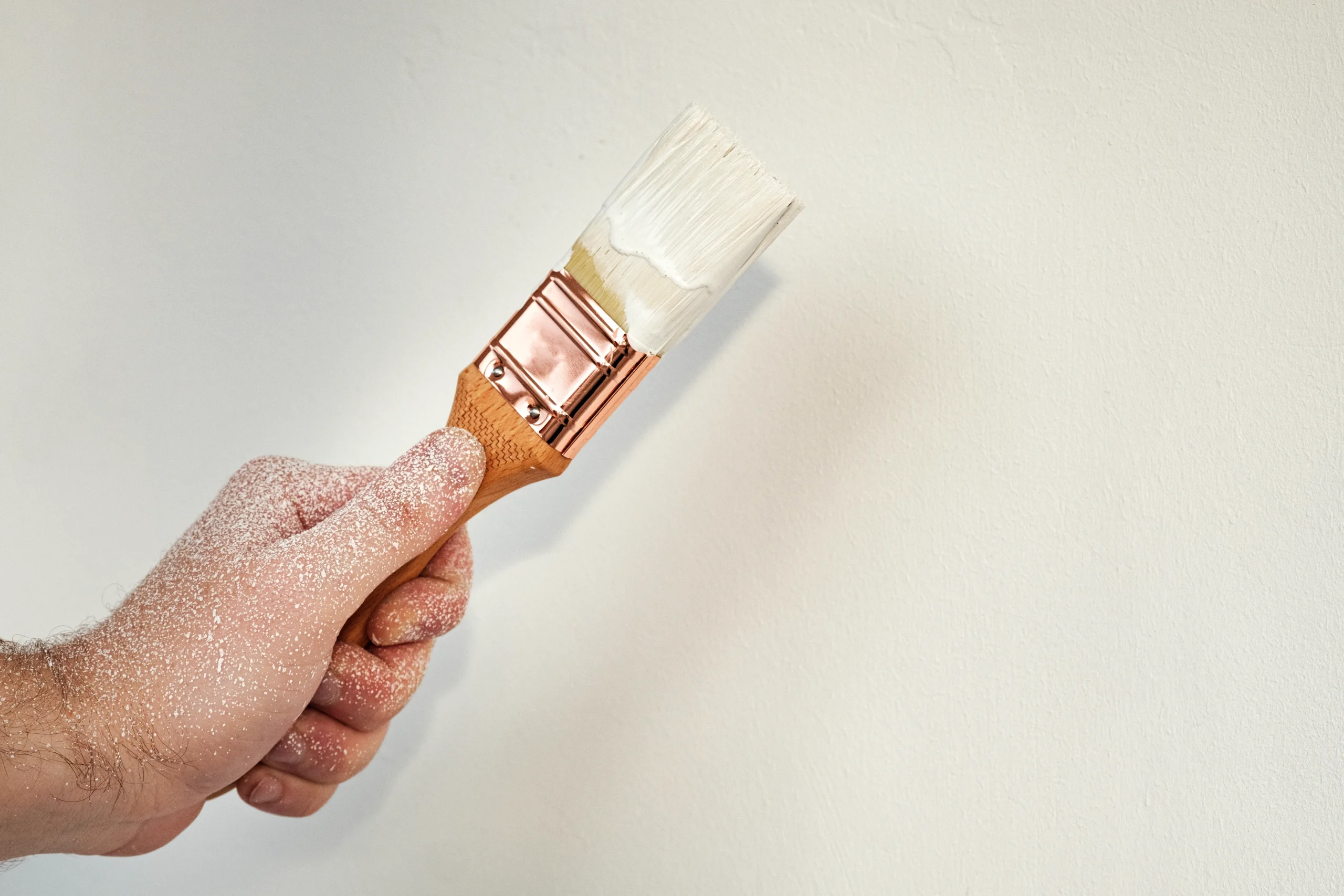 Close-up image of touching up paint on a wall with a small brush, essential for maintaining painting.